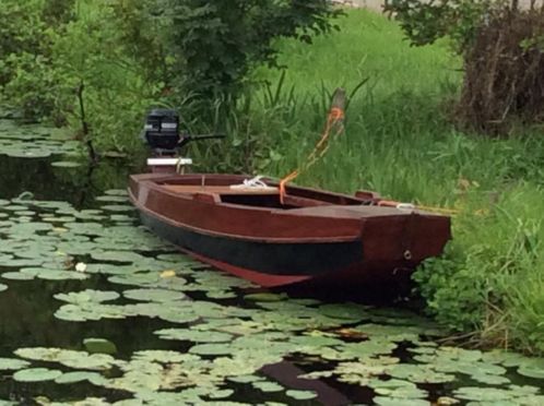 Gerenoveerde houten platbodem roeiboot met motor.