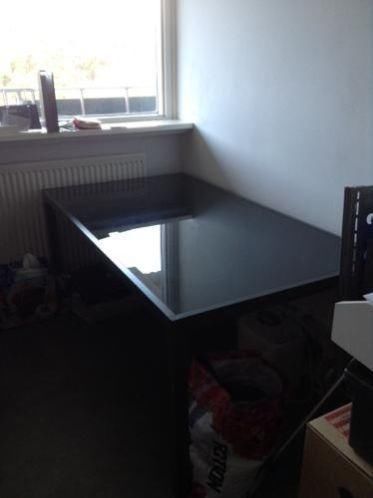 Grote grijze aluminium tuintafel met glazen bovenblad aang.