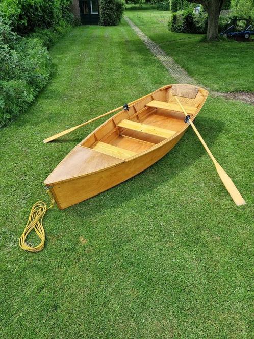 Nette houten roeiboot met roeispanen en transportwielen