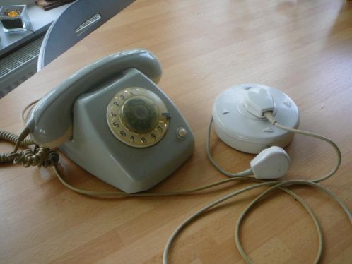 Oude telefoon met draaischijf, snoer en losse telefoonhaspel