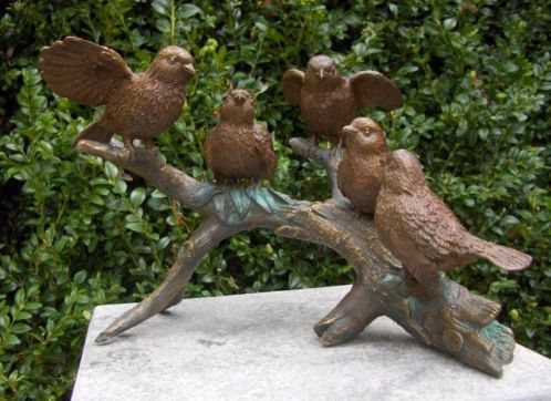 Vijf bronzen vogeltjes op een tak.