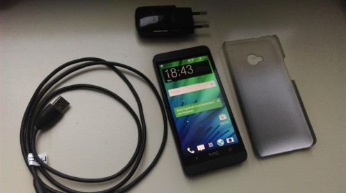 Zwarte HTC One M7 met oplader, usb-kabel en case.